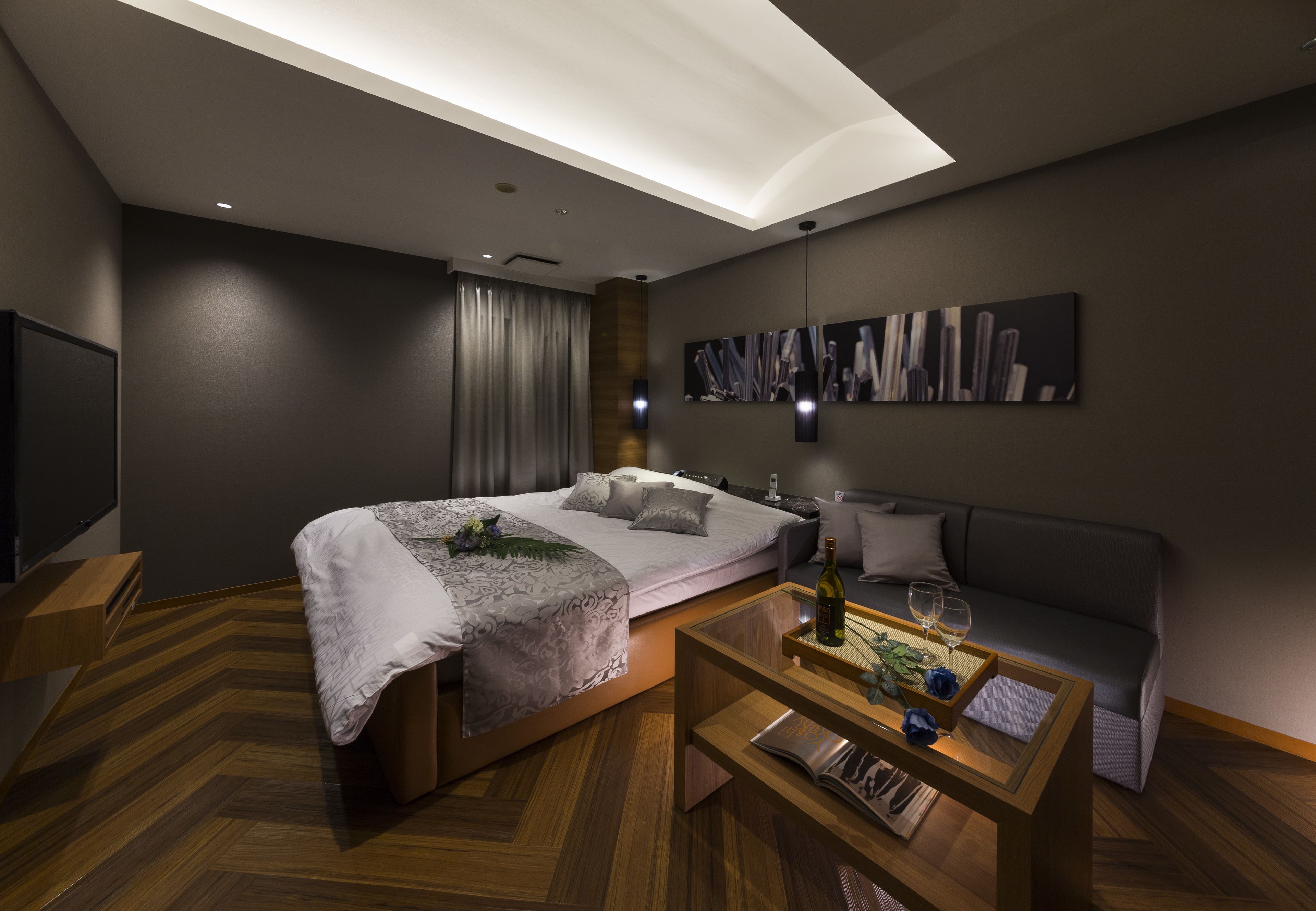 Un dormitorio moderno con una cama grande, un sofá, una mesita de centro y un cuadro en la pared.