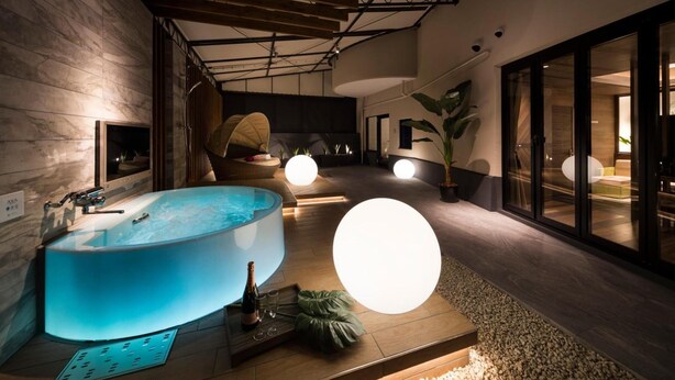 A modern spa area with a large blue bathtub, a hanging chair, and a large spherical light fixture. - Hotel Plant -garden Resort- Adult Only (Toyokawa)
