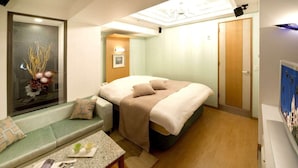 A compact hotel room with a bed, a seating area with a table, and a framed artwork on the wall. - Hotel & SPA Island Adult Only (Toyota)