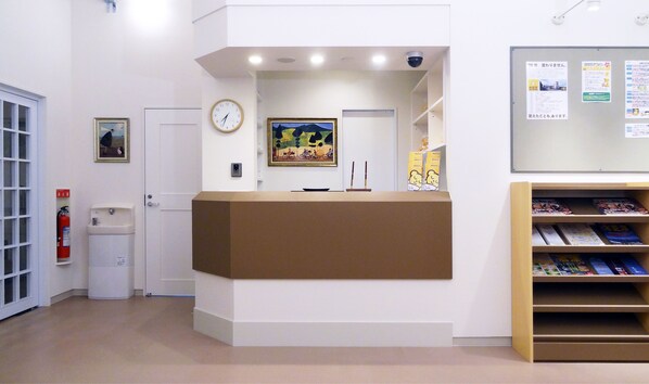 Un espace d’accueil comprenant un comptoir de réception, une horloge, un extincteur, un tableau et un panneau d’affichage.