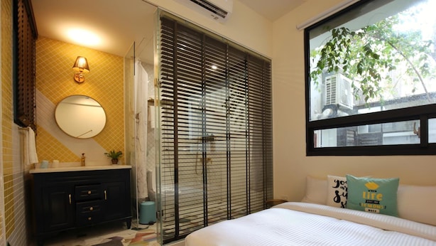 A bedroom with a bed, a window with a view, a bathroom with a sink and mirror, and a sliding door. - Yes Yes I am Willing (Tainan)
