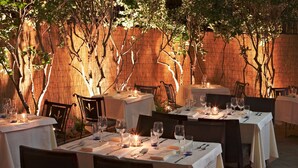An outdoor dining area with tables set for a meal, surrounded by bamboo walls and trees. - Presley Pad (Atlanta)