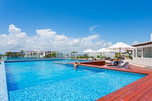 Ein Schwimmbecken mit gefliestem Sonnendeck, Liegestühlen und Sonnenschirmen.