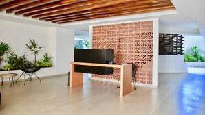 Una sala de estar moderna con techo de madera, un mueble de entretenimiento negro y una pared decorativa con patrones geométricos.