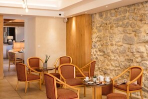 Un comedor con sillas de mimbre, una mesa redonda, un muro de piedra y un panel de madera.