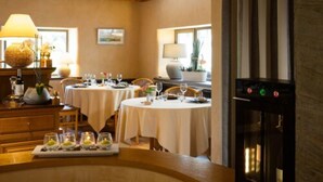 Un espace repas avec des tables rondes, des chaises et un buffet. On y trouve également une cheminée et une fenêtre laissant entrer la lumière naturelle.