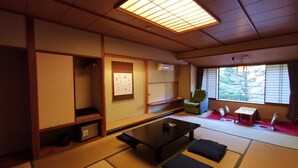A traditional Japanese room with tatami flooring, a low table, cushions, a chair, and a sliding door.