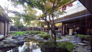 A traditional Japanese garden with a pond, rocks, and trees.