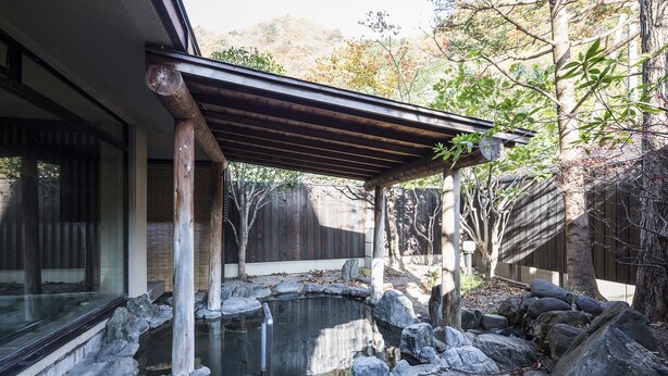 A traditional Japanese garden with a koi pond, wooden pergola, and stone lanterns.