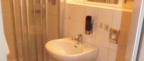 A small bathroom with a shower, sink, and toilet.