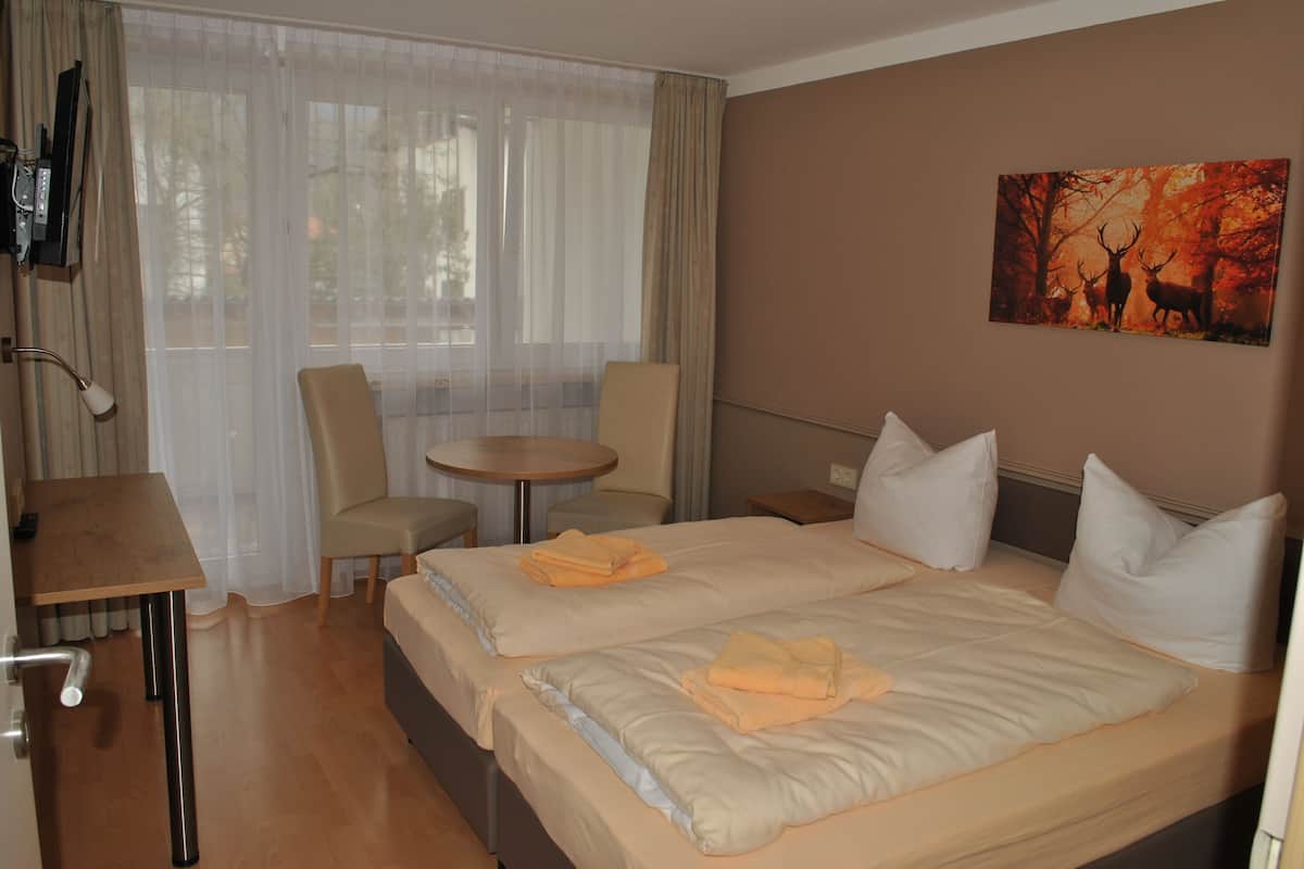 Ein Hotelzimmer mit Bett, zwei Stühlen, einem kleinen Tisch und einem Bild an der Wand.