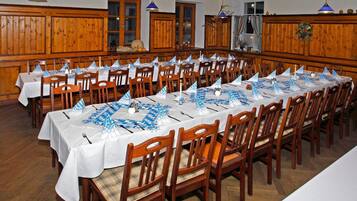 Una larga mesa de comedor dispuesta con sillas, manteles blancos y caminos de mesa azules.