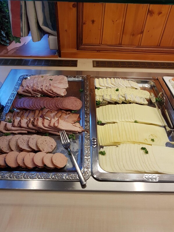 A buffet with various meats and cheeses.