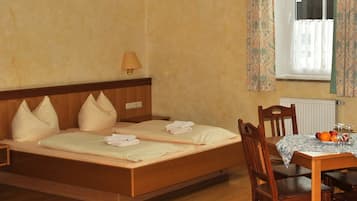 A hotel room with a wooden bed, a table with fruit, and a window with curtains.