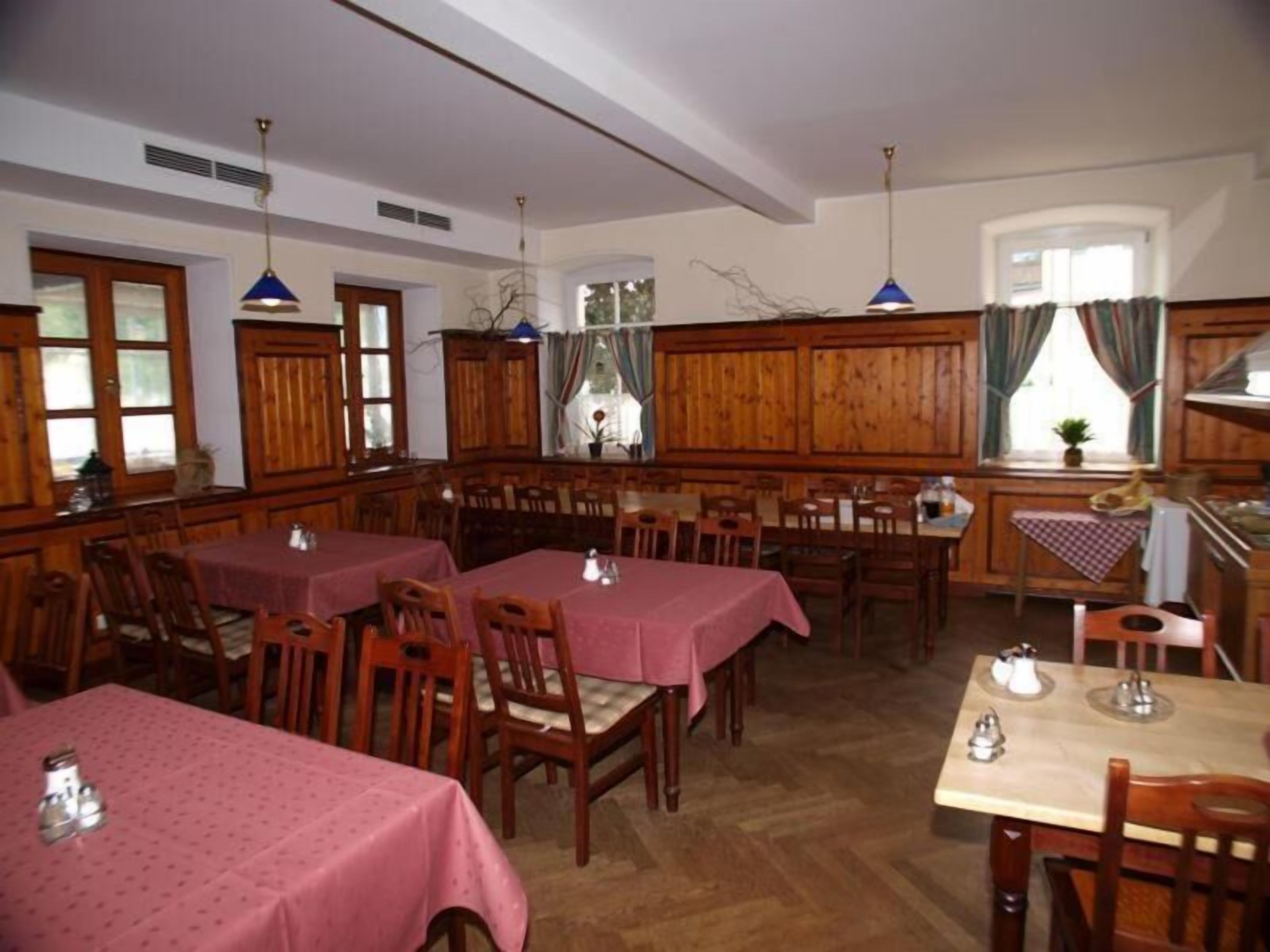 A restaurant with wooden walls and tables covered in pink tablecloths.
