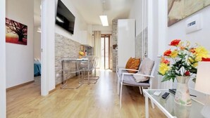 Una sala de estar moderna con una mesa de centro de vidrio, un sofá y un televisor montado en la pared.
