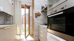 Una cocina moderna con armarios de madera, horno empotrado y salpicadero de piedra.