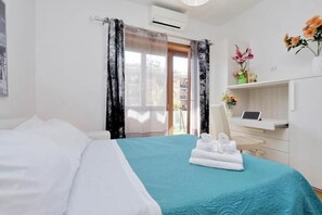 Una habitación de hotel con una cama, un escritorio con una computadora portátil y una ventana con cortinas.