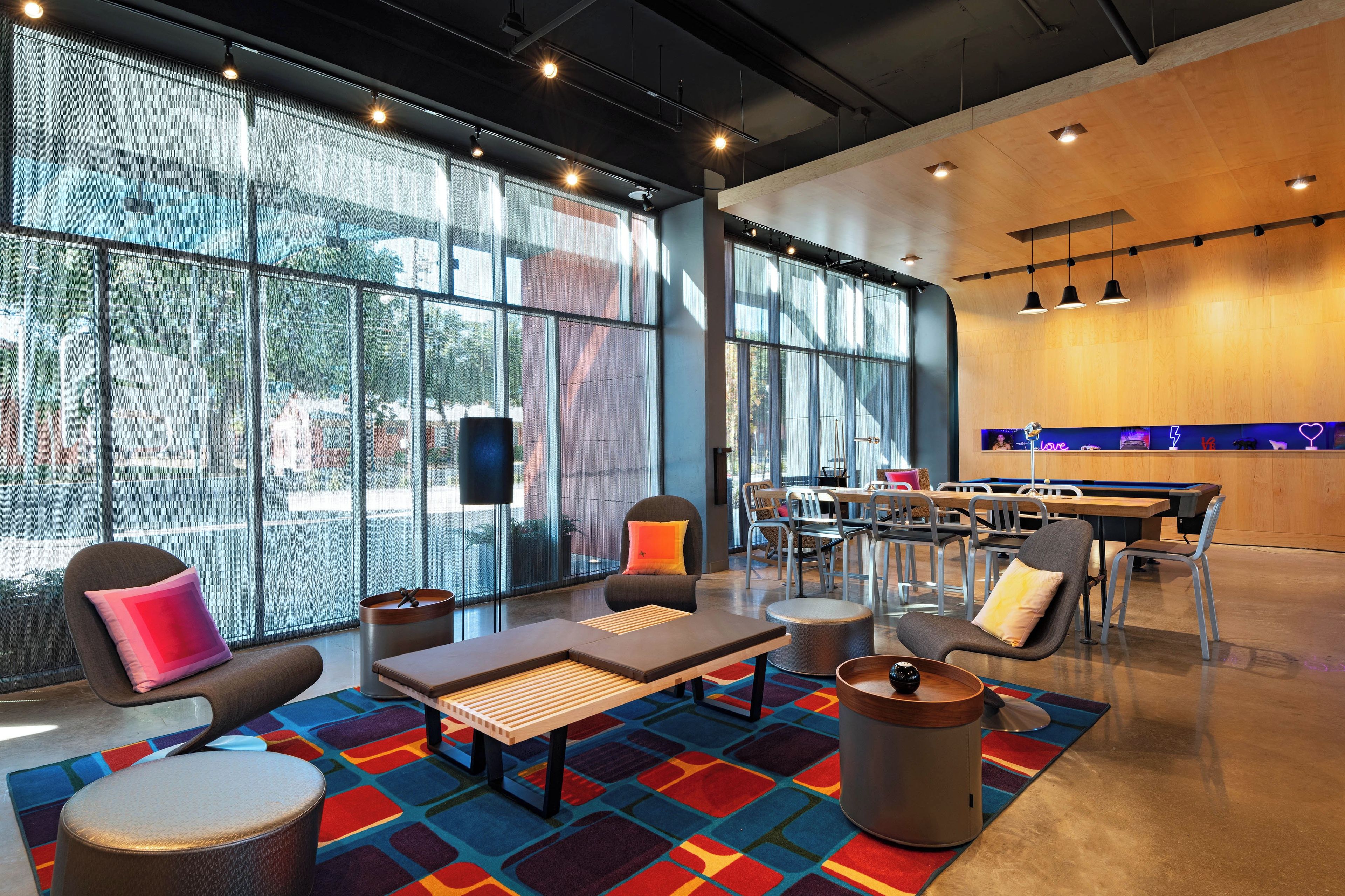 A modern lounge area with seating, a coffee table, and a bar area with a neon sign.