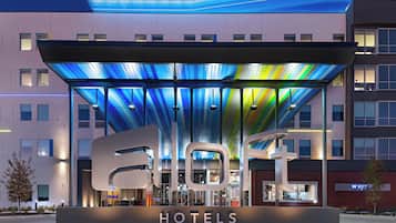 Een hotelentree met een modern ontwerp, met een grote verlichte luifel en een opvallend 'HOTELS' bord.