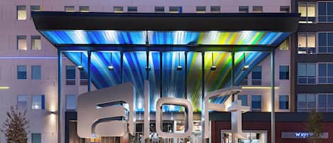 L'entrée d'un hôtel au design moderne, avec un grand auvent illuminé et une enseigne bien visible indiquant « HÔTELS ».