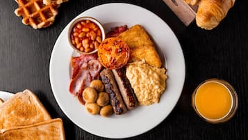 Un plat amb aliments per esmorzar, com torrades, salsitxes, ous, fesols i un tomàquet a la planxa.