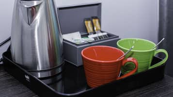 Uma bandeja preta com uma cafeteira de aço inoxidável, uma caneca vermelha e uma caneca verde.