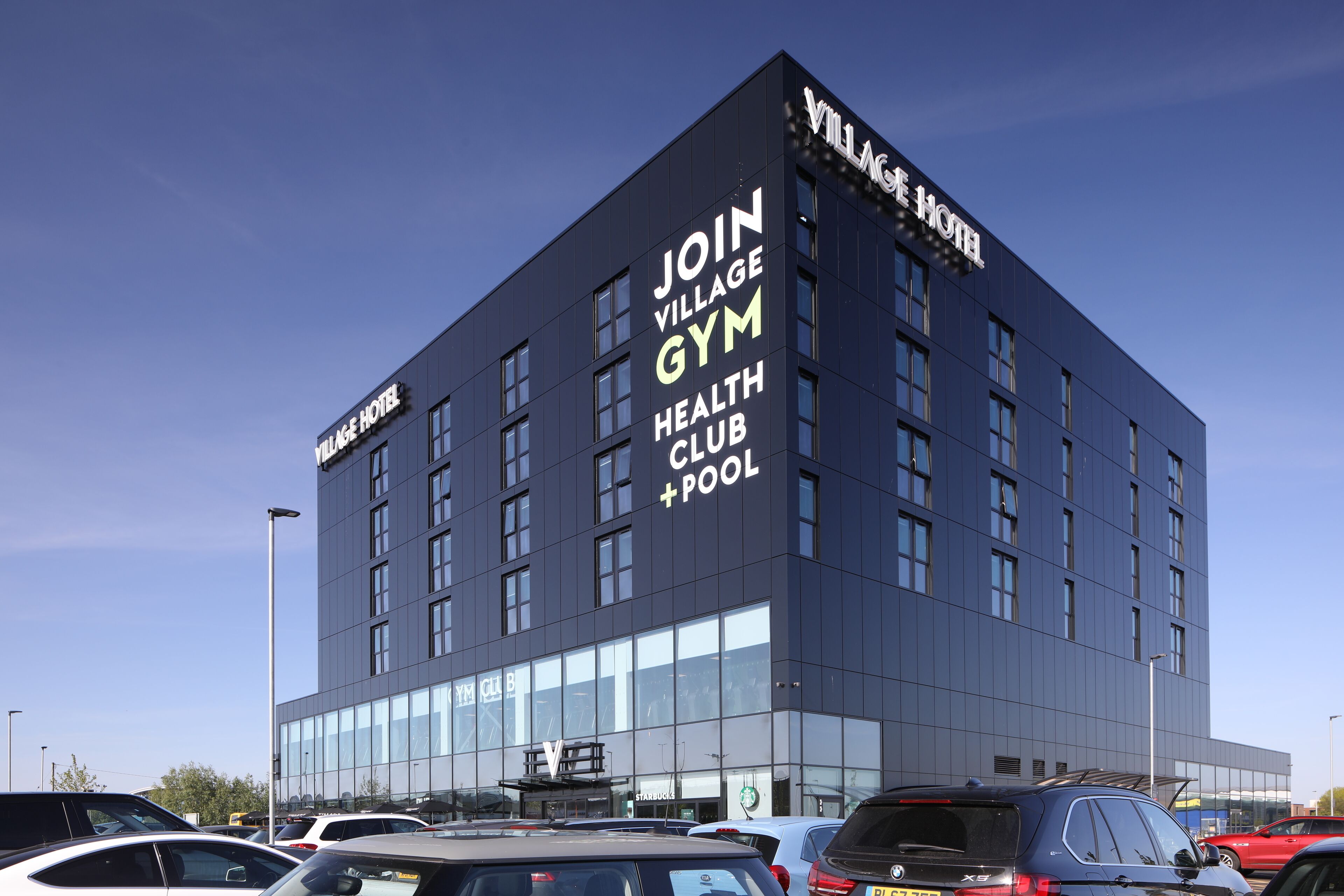 Un bâtiment moderne avec une enseigne publicitaire pour une salle de sport, un club de remise en forme et une piscine.