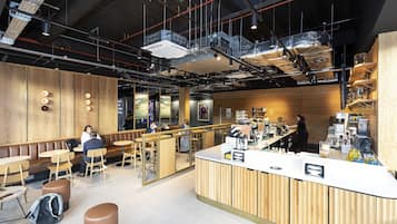 A modern cafe with wooden booths, a bar area, and a counter with various items.