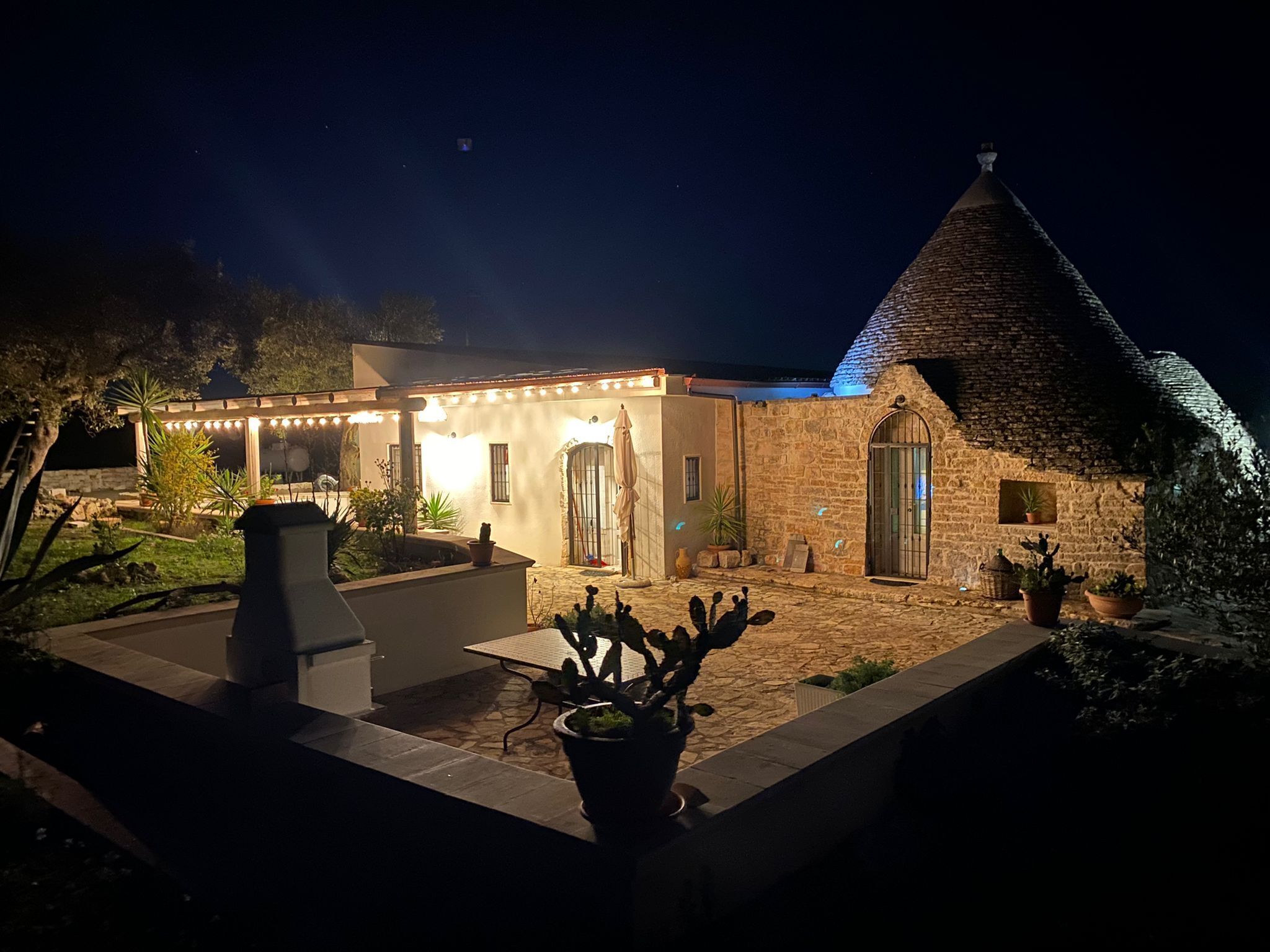 A stone building with a tiled patio, a covered seating area, and potted plants.