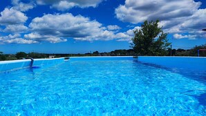 Ein klares, blaues Schwimmbecken mit Blick auf den Himmel und ferne Bäume.