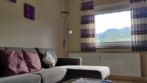 Una sala de estar con un sofá, una lámpara de pie y una ventana con cortinas.