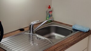 Una cocina con microondas integrado, pileta de acero inoxidable y encimeras de madera.