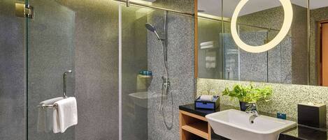A modern bathroom with a glass-enclosed shower, a sink with a mirror, and a potted plant.