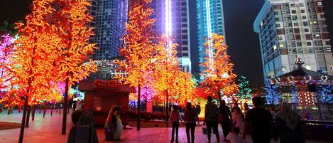 A nighttime urban scene with illuminated trees and tall buildings.