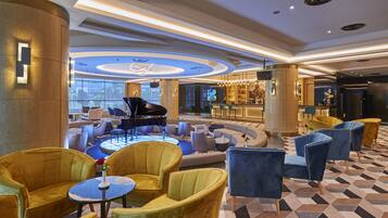 A spacious lobby with a grand piano, plush seating, and a bar area.