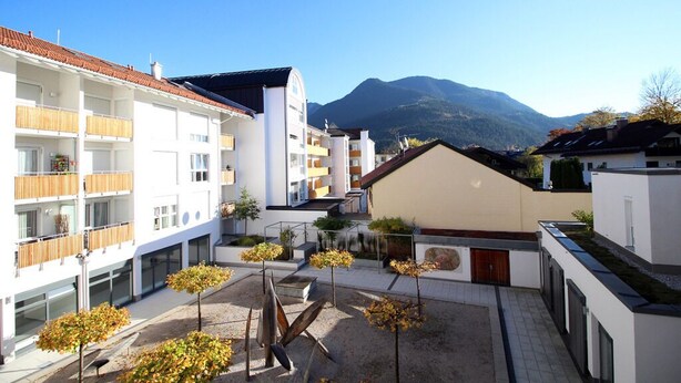 Um edifício moderno com várias varandas e um pátio com árvores.