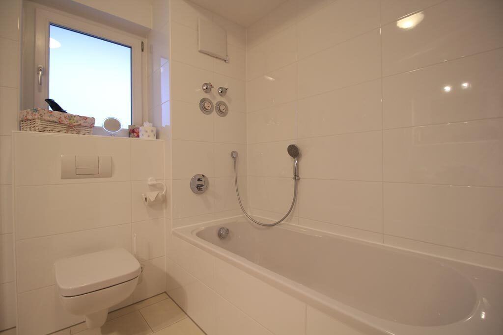 A bathroom with a toilet, a bathtub, and a window.