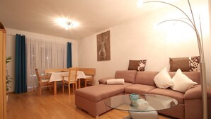 Uma sala de estar moderna com um sofá modular, uma mesa de centro de vidro e uma área de jantar com mesa e cadeiras.