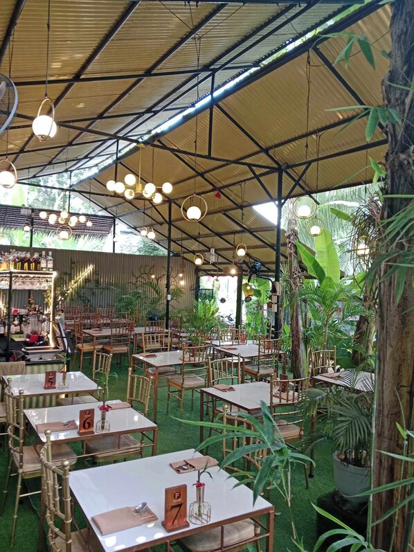 An indoor restaurant with multiple tables and chairs, a bar area, and various plants. - Ecostay (Panglao)