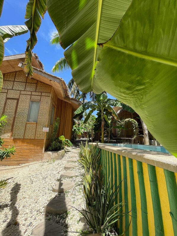 Un complexe hôtelier tropical doté d’une piscine, de palmiers et d’un bâtiment à toit de chaume.