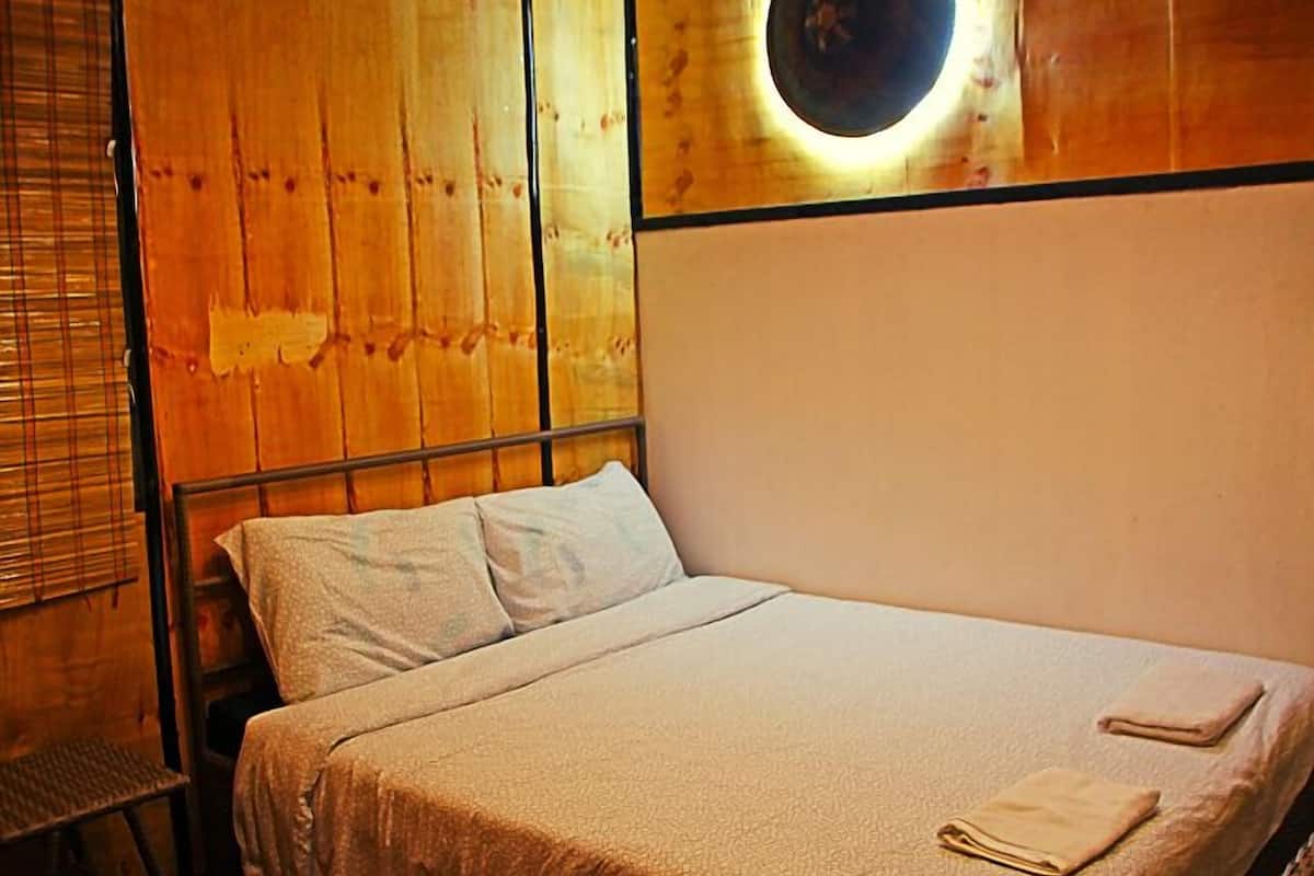 A single bed with a headboard, a bedside table, and a wall-mounted circular light fixture.