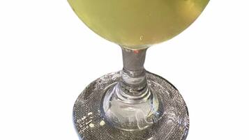 Un verre à cocktail avec une paille, contenant un liquide jaunâtre et des rondelles de citron vert.