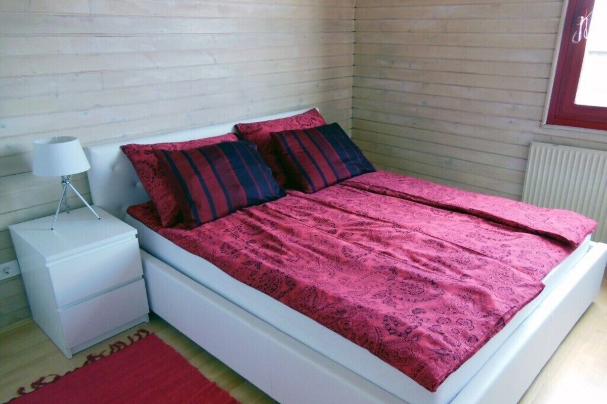 Une chambre à coucher avec un lit, une table de chevet, une lampe et une fenêtre.