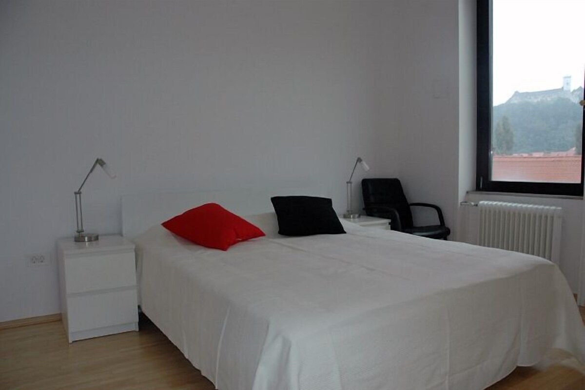 Une chambre simple et épurée, avec un lit, deux tables de chevet et une chaise.