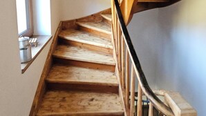 A wooden staircase with a black railing, leading to a landing with a window. - Arrive and feel good in the exclusive and modern Chalet Weitsee (Reit im Winkl)