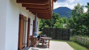 A rustic wooden building with a patio area, outdoor seating, and a view of a mountain. - Arrive and feel good in the exclusive and modern Chalet Weitsee (Reit im Winkl)