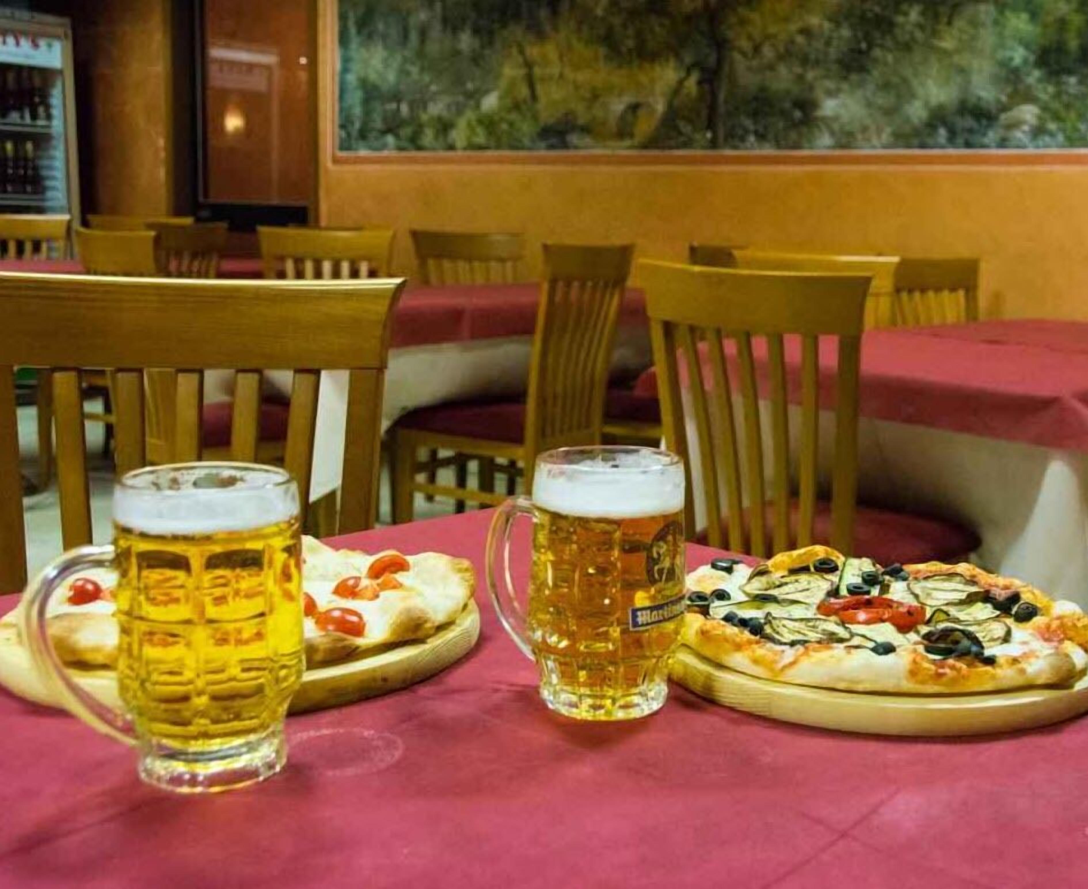 Un tavolo con due boccali di birra e una pizza con verdure.