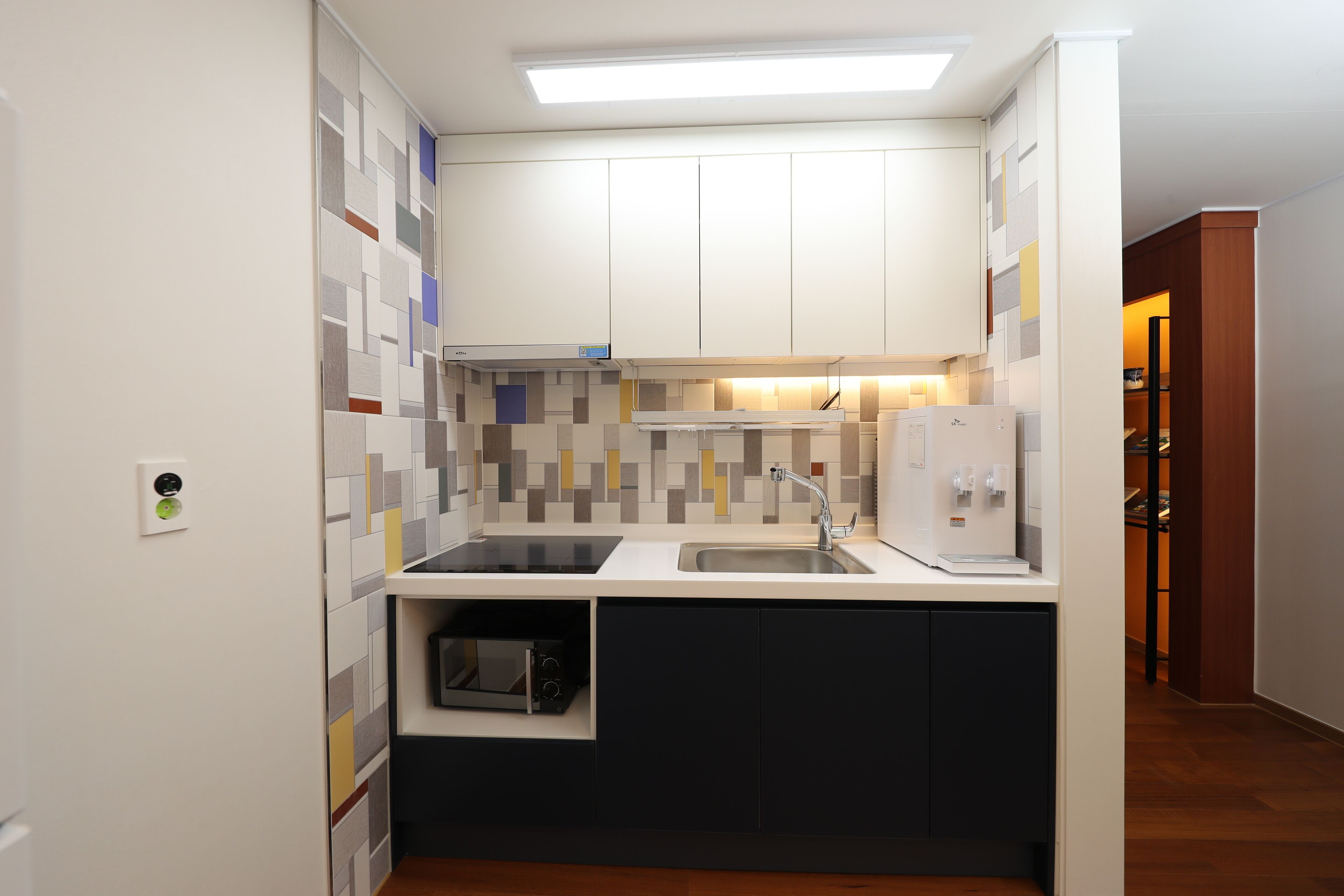 A compact kitchen with a microwave, sink, and a built-in oven.