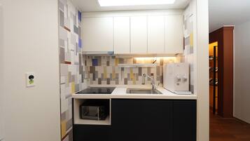A compact kitchen with a microwave, sink, and a built-in oven.